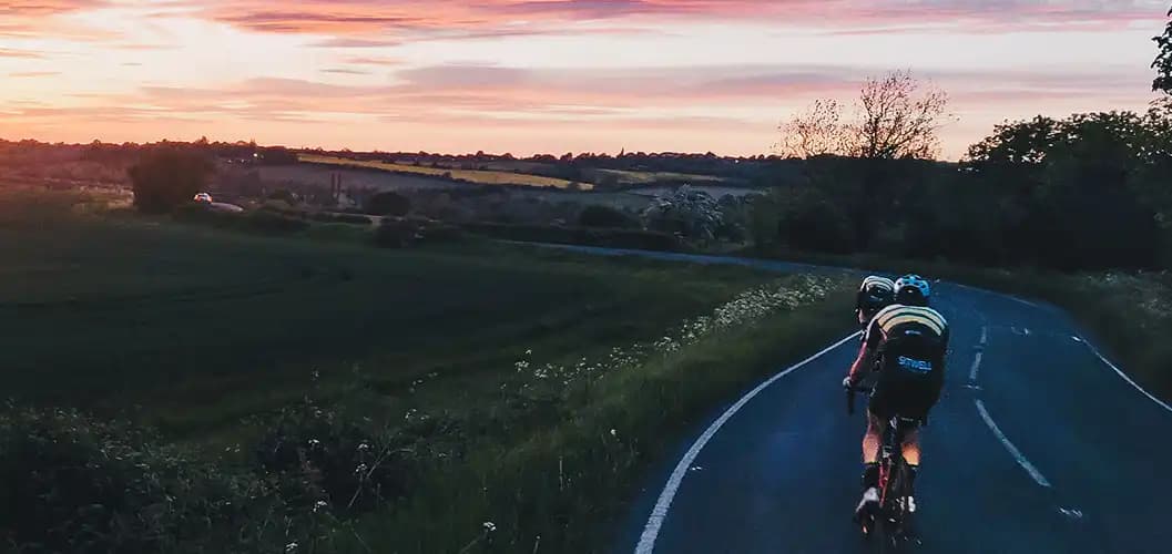 A landscape photograph of a sunset over Whiston with two Club riders up front