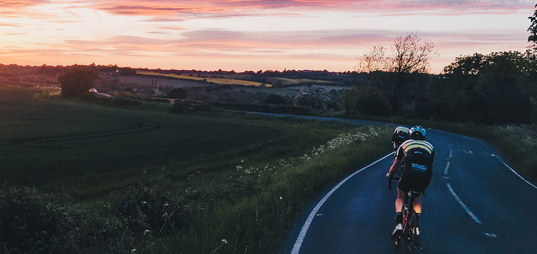 A landscape photograph of a sunset over Whiston with two Clib riders up front