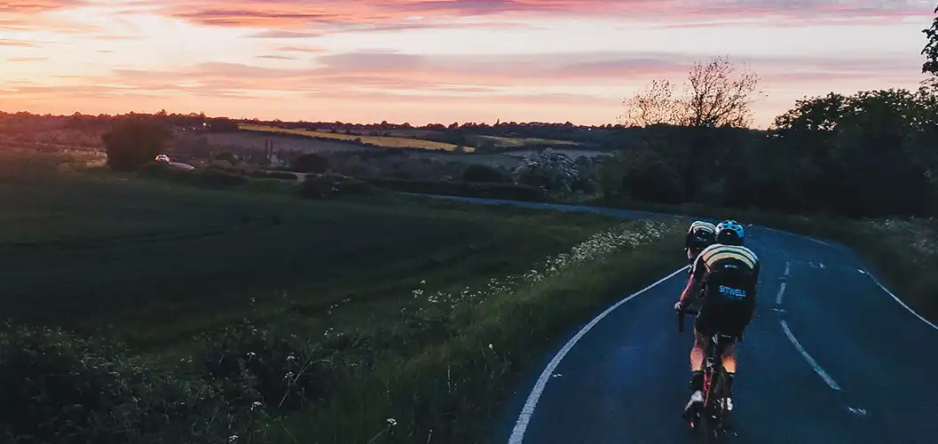 A landscape photograph of a sunset over Whiston with two Club riders up front